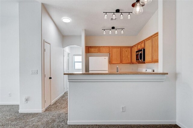 5521 Jackpot Winner Ln Unit 101, Las Vegas, NV 89122 - kitchen with stainless steel microwave, freestanding refrigerator, arched walkways, a peninsula, and light carpet