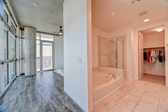 353 E Bonneville Ave Unit 313, Las Vegas, NV 89101 - bathroom with a stall shower, a bath, a walk in closet, a wall of windows, and wood finished floors