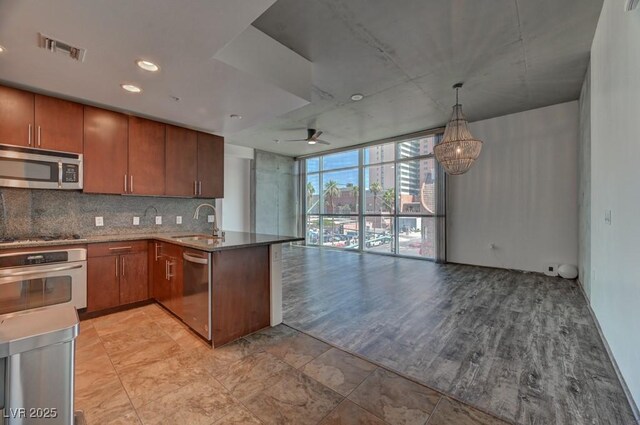 353 E Bonneville Ave Unit 313, Las Vegas, NV 89101 - kitchen with appliances with stainless steel finishes, floor to ceiling windows, a peninsula, open floor plan, and brown cabinetry