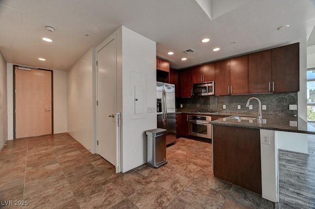 353 E Bonneville Ave Unit 313, Las Vegas, NV 89101 - kitchen featuring appliances with stainless steel finishes, a peninsula, backsplash, dark stone counters, and recessed lighting