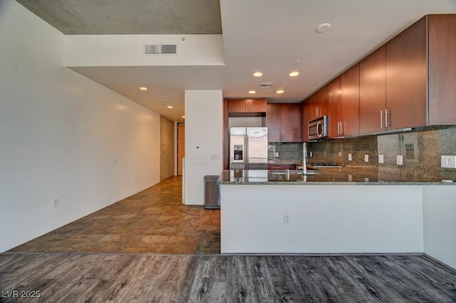 353 E Bonneville Ave Unit 313, Las Vegas, NV 89101 - kitchen with stainless steel appliances, dark stone counters, a peninsula, decorative backsplash, and recessed lighting