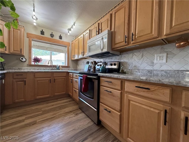 1829 Campton St, Ely, NV 89301 - kitchen featuring stainless steel range with electric cooktop, white microwave, backsplash, light wood-style flooring, and a textured ceiling