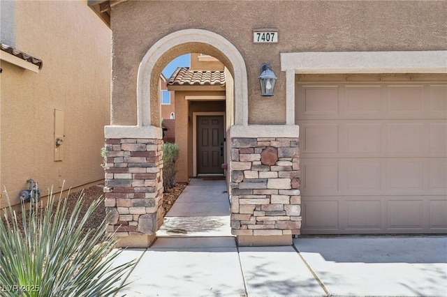 7407 Bakewell Ave, Las Vegas, NV 89179 - view of exterior entry featuring stucco siding, a garage, a tiled roof, and stone siding