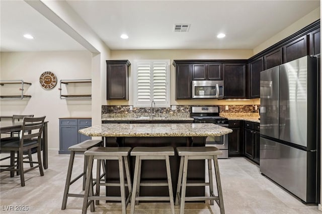 7407 Bakewell Ave, Las Vegas, NV 89179 - kitchen featuring stainless steel appliances, light stone countertops, a kitchen bar, a center island, and dark brown cabinetry