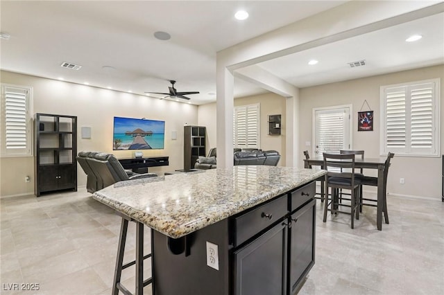 7407 Bakewell Ave, Las Vegas, NV 89179 - kitchen featuring ceiling fan, light stone counters, recessed lighting, a breakfast bar area, and light tile patterned floors