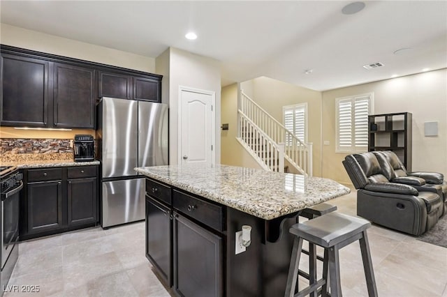 7407 Bakewell Ave, Las Vegas, NV 89179 - kitchen featuring freestanding refrigerator, a kitchen breakfast bar, open floor plan, light stone countertops, and a kitchen island