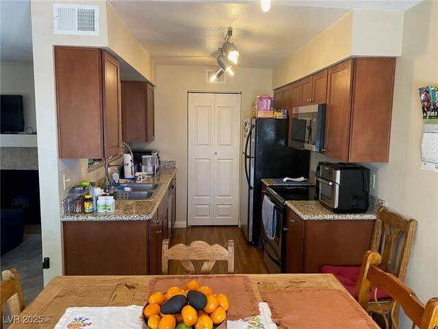 2750 S Durango Dr Unit 2141, Las Vegas, NV 89117 - kitchen featuring appliances with stainless steel finishes, dark wood-style flooring, brown cabinetry, light countertops, and a tiled fireplace