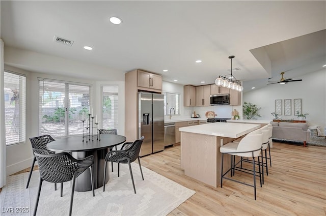 8813 Sundial Dr, Las Vegas, NV 89134 - kitchen with appliances with stainless steel finishes, a center island, light wood finished floors, light countertops, and open floor plan