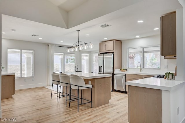 8813 Sundial Dr, Las Vegas, NV 89134 - kitchen with stainless steel appliances, a kitchen breakfast bar, light wood-type flooring, light countertops, and recessed lighting