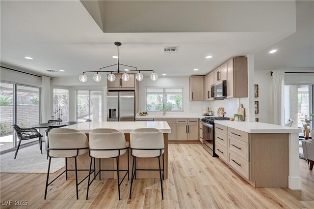 8813 Sundial Dr, Las Vegas, NV 89134 - kitchen with stainless steel appliances, a breakfast bar, plenty of natural light, light wood-style floors, and recessed lighting