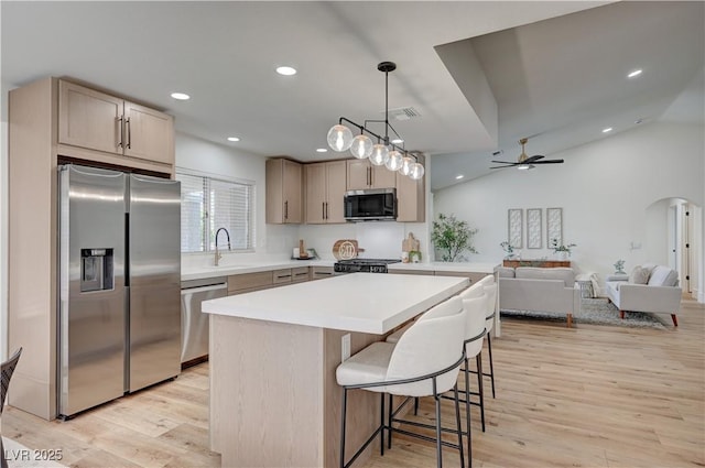 8813 Sundial Dr, Las Vegas, NV 89134 - kitchen with appliances with stainless steel finishes, a center island, light wood-type flooring, a kitchen breakfast bar, and recessed lighting