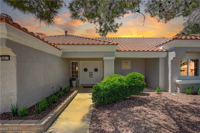 8813 Sundial Dr, Las Vegas, NV 89134 - exterior entry at dusk featuring a tile roof and stucco siding
