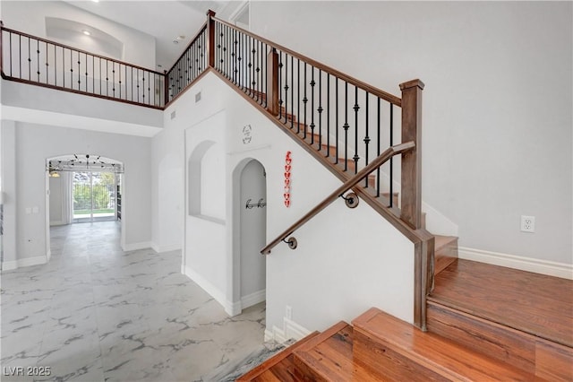 3079 Evening Mist Ave, Henderson, NV 89052 - staircase featuring arched walkways, marble finish floors, and a high ceiling