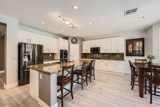 6103 Sundown Crest St, Las Vegas, NV 89113 - kitchen with black appliances, a kitchen bar, backsplash, light wood-style floors, and white cabinets
