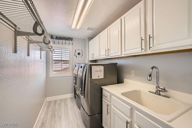 6103 Sundown Crest St, Las Vegas, NV 89113 - washroom featuring washing machine and dryer, cabinet space, light wood finished floors, and a textured ceiling