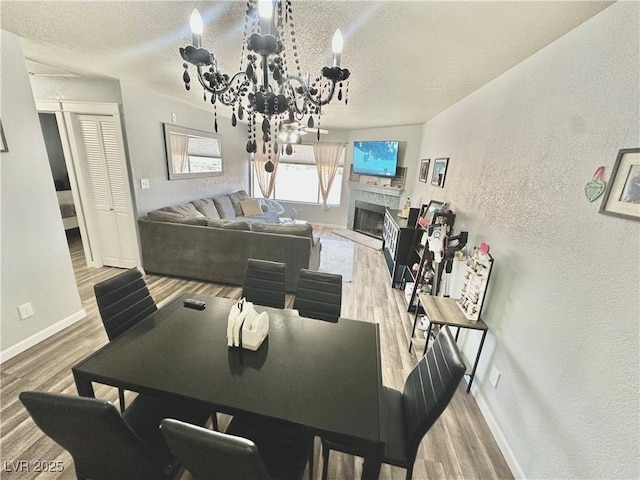 2016 Mesquite Ln Unit 302, Laughlin, NV 89029 - dining space featuring wood finished floors, a fireplace with raised hearth, a chandelier, a textured ceiling, and a textured wall
