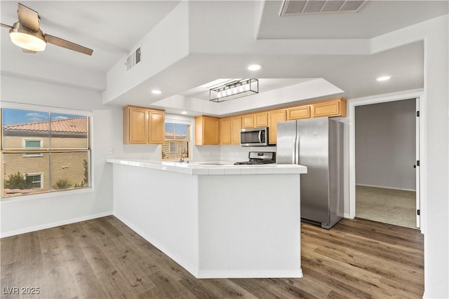 3608 Quetonia St Unit 204, Las Vegas, NV 89108 - kitchen featuring stainless steel appliances, tile counters, wood finished floors, a peninsula, and recessed lighting
