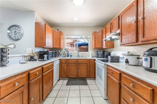 4656 E Desert Inn Rd, Las Vegas, NV 89121 - kitchen with white appliances, under cabinet range hood, brown cabinets, light countertops, and light tile patterned floors