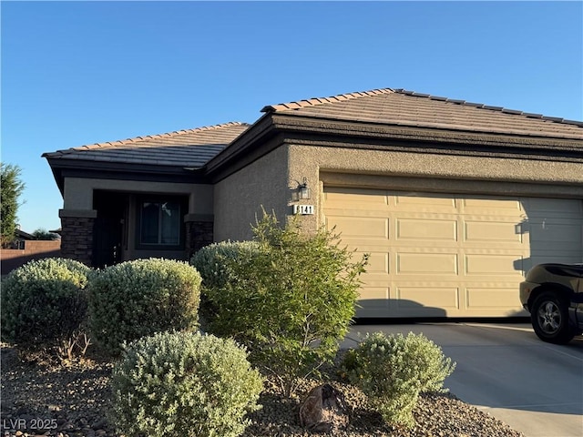 6141 Tokara Ave, Las Vegas, NV 89122 - view of front of home with a tile roof, a garage, stucco siding, concrete driveway, and stone siding