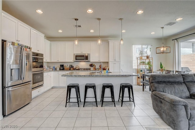 4240 Spring Storm Ave, North Las Vegas, NV 89081 - kitchen featuring stainless steel appliances, open floor plan, healthy amount of natural light, a kitchen breakfast bar, and recessed lighting
