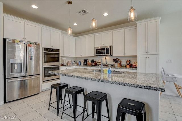 4240 Spring Storm Ave, North Las Vegas, NV 89081 - kitchen featuring appliances with stainless steel finishes, light tile patterned flooring, a breakfast bar, white cabinetry, and recessed lighting