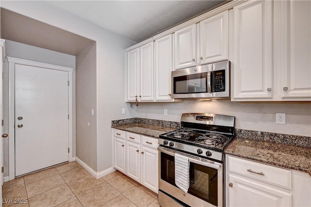 7704 Lots Hills Dr, Las Vegas, NV 89179 - kitchen featuring appliances with stainless steel finishes, white cabinetry, light tile patterned flooring, and dark stone counters