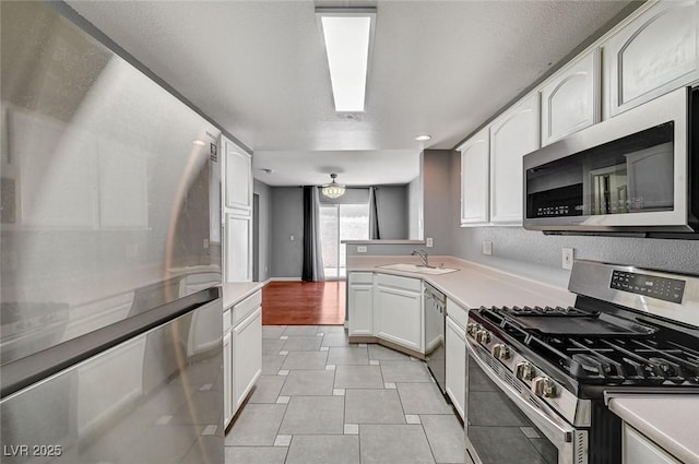 198 Winterport St, Henderson, NV 89074 - kitchen with stainless steel appliances, white cabinetry, a peninsula, light tile patterned floors, and light countertops
