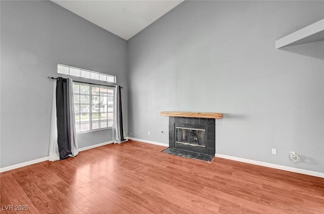 198 Winterport St, Henderson, NV 89074 - unfurnished living room with high vaulted ceiling, a tile fireplace, and wood finished floors