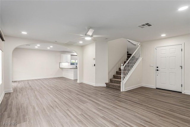 9006 Cedar Door Ave, Las Vegas, NV 89148 - unfurnished living room with arched walkways, ceiling fan, light wood finished floors, stairway, and recessed lighting