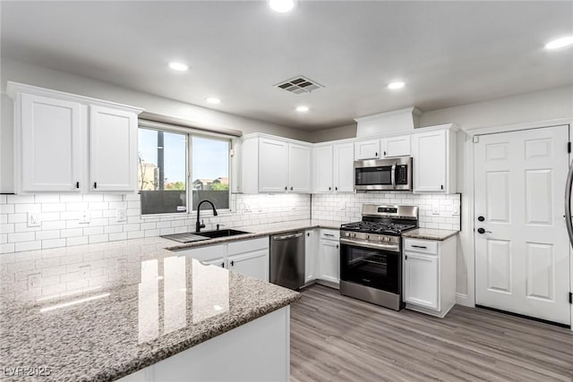 9006 Cedar Door Ave, Las Vegas, NV 89148 - kitchen with appliances with stainless steel finishes, white cabinetry, light stone countertops, decorative backsplash, and recessed lighting
