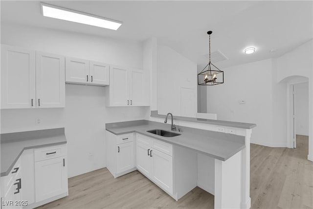 9315 Indian Corn Ct Unit 101, Las Vegas, NV 89178 - kitchen with a peninsula, white cabinets, light wood-style floors, and vaulted ceiling