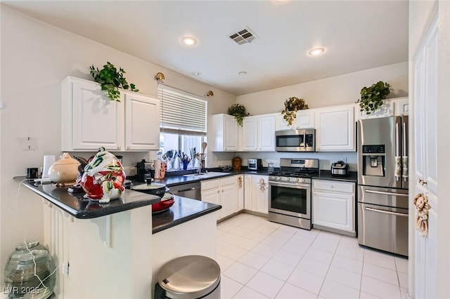 5409 Flora Spray St, Las Vegas, NV 89130 - kitchen featuring appliances with stainless steel finishes, a peninsula, white cabinets, dark countertops, and light tile patterned floors