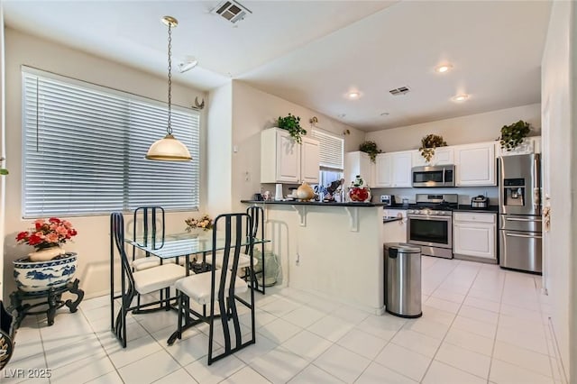 5409 Flora Spray St, Las Vegas, NV 89130 - kitchen with stainless steel appliances, dark countertops, decorative light fixtures, a peninsula, and a kitchen bar