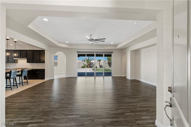 9240 Northfield Park Ct, Las Vegas, NV 89148 - unfurnished living room with arched walkways, dark wood-type flooring, a ceiling fan, a tray ceiling, and recessed lighting