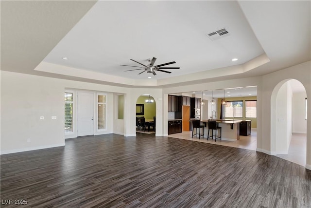 9240 Northfield Park Ct, Las Vegas, NV 89148 - unfurnished living room featuring a tray ceiling, arched walkways, wood finished floors, and recessed lighting