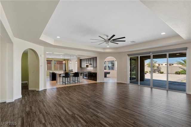 9240 Northfield Park Ct, Las Vegas, NV 89148 - unfurnished living room featuring a raised ceiling, arched walkways, wood finished floors, ceiling fan, and recessed lighting