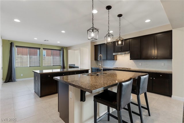 9240 Northfield Park Ct, Las Vegas, NV 89148 - kitchen with an island with sink, decorative backsplash, a breakfast bar, light tile patterned floors, and recessed lighting