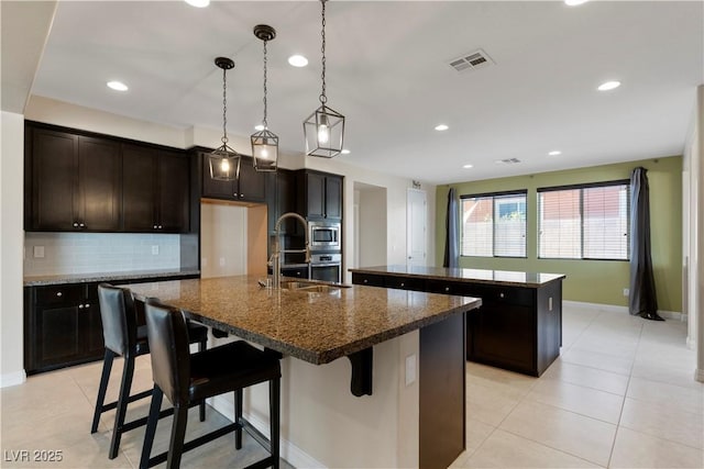 9240 Northfield Park Ct, Las Vegas, NV 89148 - kitchen featuring a center island with sink, decorative backsplash, stainless steel appliances, recessed lighting, and a breakfast bar area