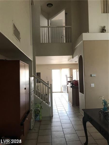 8769 Country View Ave, Las Vegas, NV 89129 - hallway featuring tile patterned flooring, a towering ceiling, arched walkways, and stairs