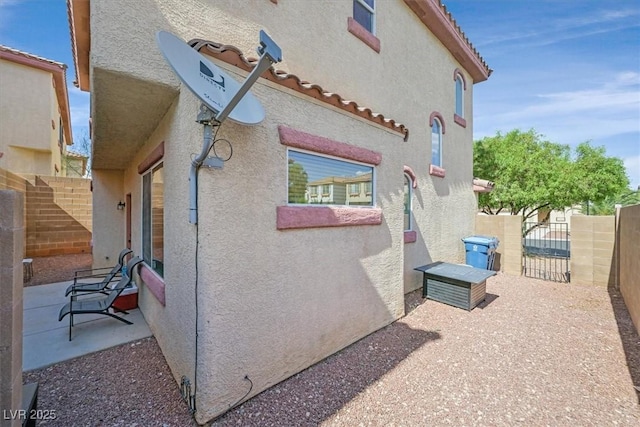 10601 Lessona St, Las Vegas, NV 89141 - view of side of home with stucco siding, a patio area, a gate, and a tiled roof