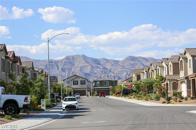 7037 Tilligerry St, North Las Vegas, NV 89084 - view of asphalt street with a residential view, a mountain view, street lights, and sidewalks