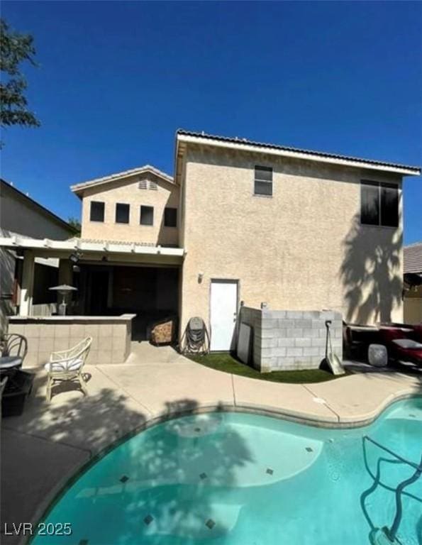 9801 Bradford Summit St, Las Vegas, NV 89183 - rear view of house featuring stucco siding, a patio, and an outdoor pool