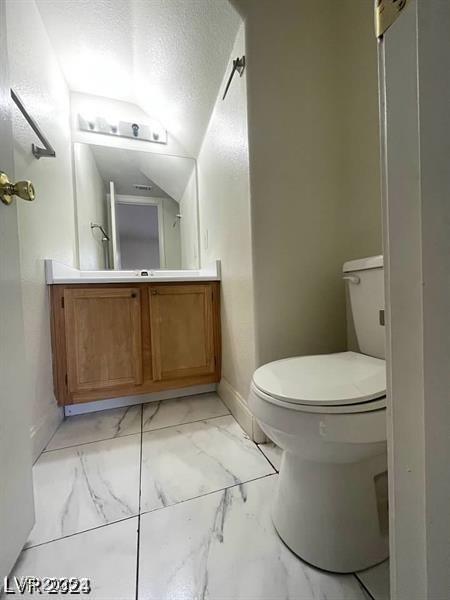 9617 Pine River Ln, Las Vegas, NV 89123 - half bath with marble look tile flooring, vanity, a textured ceiling, and lofted ceiling