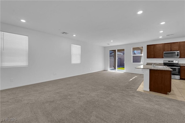 5677 Asyma Ct, Las Vegas, NV 89113 - kitchen with appliances with stainless steel finishes, open floor plan, recessed lighting, light colored carpet, and an island with sink