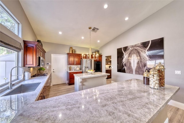 7311 Chaparral Cove Ln, Las Vegas, NV 89131 - kitchen featuring stainless steel appliances, light wood-style floors, a center island, light stone counters, and tasteful backsplash