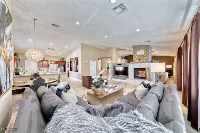7311 Chaparral Cove Ln, Las Vegas, NV 89131 - living room with light wood-style floors, recessed lighting, a chandelier, a tiled fireplace, and a textured ceiling