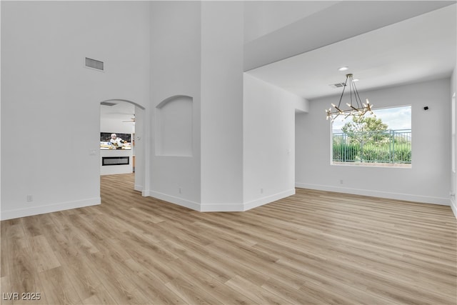 1551 Boundary Peak Way, Las Vegas, NV 89135 - unfurnished room with a chandelier, light wood-type flooring, arched walkways, and a towering ceiling