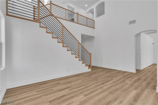 1551 Boundary Peak Way, Las Vegas, NV 89135 - unfurnished living room featuring arched walkways, a high ceiling, stairway, wood finished floors, and recessed lighting