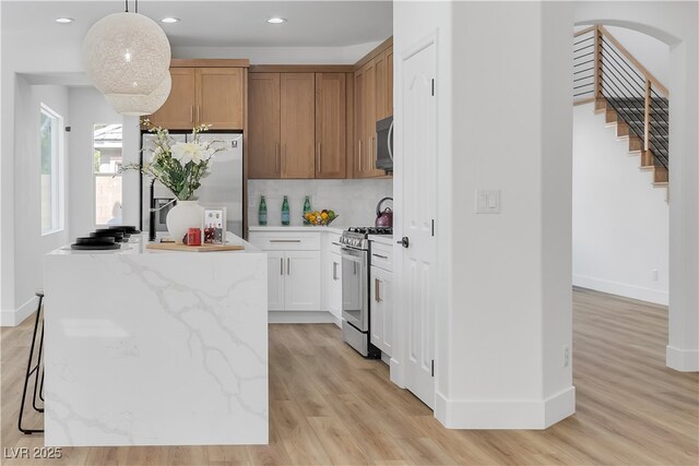 1551 Boundary Peak Way, Las Vegas, NV 89135 - kitchen with appliances with stainless steel finishes, backsplash, light wood-style floors, recessed lighting, and pendant lighting