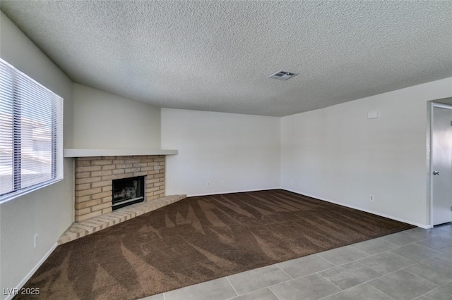 1013 Falconhead Ln Unit 202, Las Vegas, NV 89128 - unfurnished living room featuring carpet, a textured ceiling, a brick fireplace, and tile patterned flooring